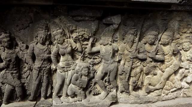Ancient relief carvings of mythical figures on stone wall at Borobudur temple in Indonesia.