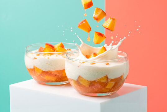 Dynamic flying peach and Greek yogurt parfait splash in glass bowls on a vibrant bicolor background