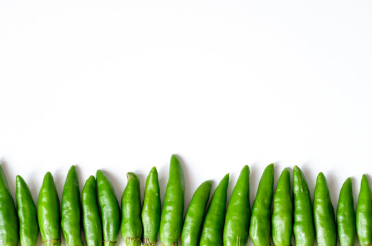 Organized horizontal rows of fresh green bird's eye chilies or cabe rawit hijau on white background
