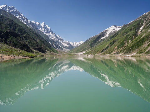 Colorful landscape view of Saiful Muluk lake with reflection of snowcapped mountains in water near Naran, Kaghan valley, Khyber Pakhtunkhwa, Pakistan