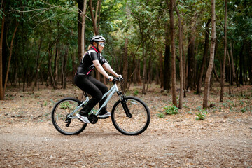 Fototapeta premium Focused blonde woman riding bicycle along dirt path in green woods