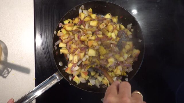 Hirtshals, Denmark A cook prepares onions, apples and meat in a frying pan to make South African bobotie.