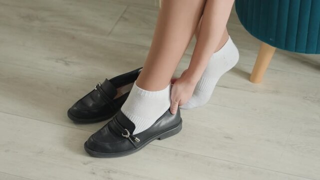 Caucasian woman slipping into loafers house quick morning prep for work with white socks and leather buckled shoes, focused motion, tidy entryway, polished floor, ready for commute