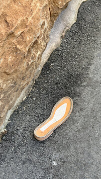 Lost Shoe Sole on Asphalt Beside Sandstone Rock in Street
