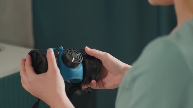 Blue respirator mask inspected caucasian woman, removing dual filters and checking valve and strap on vanity countertop homeowner performing maintenance, safety technician demonstrating filter