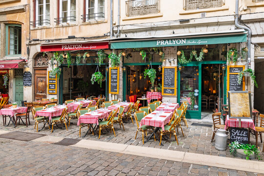 Lyon, France - 27 July 2026: Outdoor restaurant terrace of Pralyon Bouchon Lyonnais with red checkered tables on cobblestone street in old town Vieux Lyon.