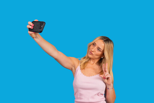 Blonde woman taking selfie showing peace sign