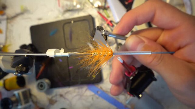Hirtshals, Denmark A man makes a fishing fly from feathers and metal wire on a desktop with tweezers and other tools. 