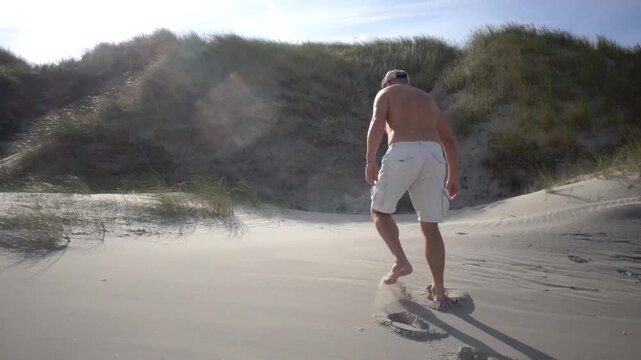 Hirtshals, Denmark A man does morning callisthenics and exercises on a sandy beach on the North Sea in summer. 