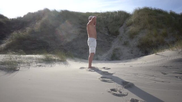 Hirtshals, Denmark A man does morning callisthenics and exercises on a sandy beach on the North Sea in summer. 