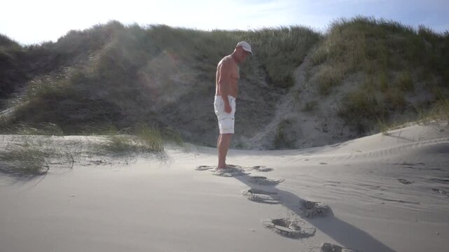 Hirtshals, Denmark A man does morning callisthenics and exercises on a sandy beach on the North Sea in summer. 