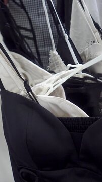 Close-up video of black and white bras and lace lingerie on hangers as a shopper browses and moves garments along a retail rack