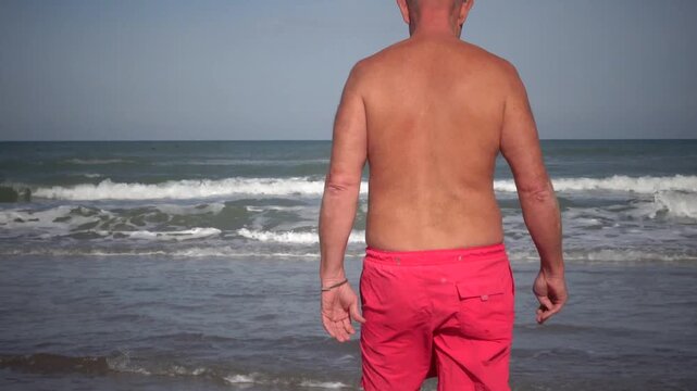 Hirtshals, Denmark A man does morning callisthenics and exercises on a sandy beach on the North Sea in summer. 
