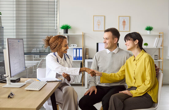 Couple and doctor consultation on pregnancy planning. Warm handshake in a bright clinic shows quality healthcare and an appointment with open discussion. Clear family planning and fertility aid.