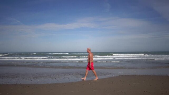 Hirtshals, Denmark A man does morning callisthenics and exercises on a sandy beach on the North Sea in summer. 