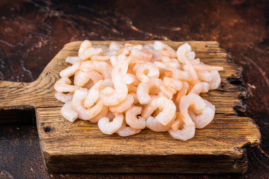 Baby shrimp pile on rustic cutting board, cocktail shrimp ingredient for salads, tapas, pasta and gourmet seafood recipes.