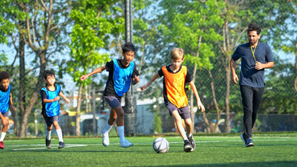 Fototapeta premium Football coach training international school students on the field,