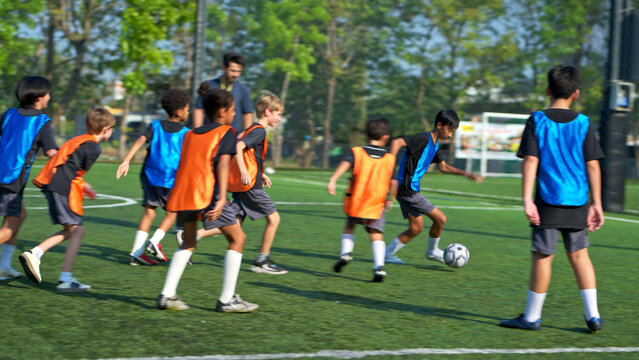 Football coach training international school students on the field,