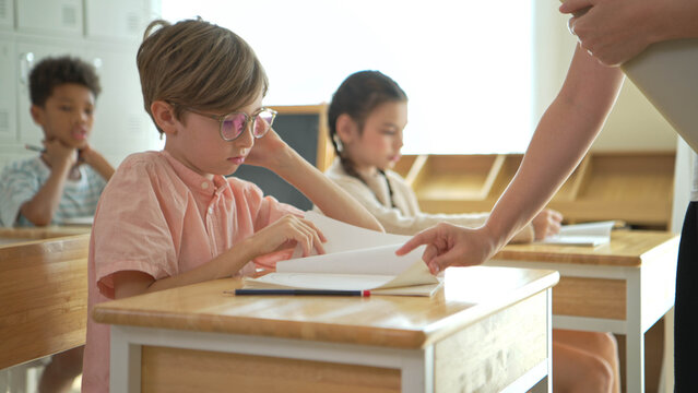 Schoolboy looking bored and distracted in classroom while classmates study,