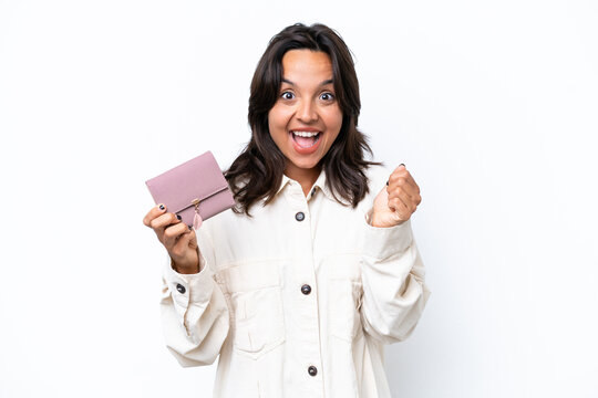 Young hispanic woman holding wallet isolated on white background celebrating a victory in winner position