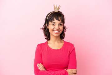 Young mixed race princess with crown isolated on pink background keeping the arms crossed in frontal position © luismolinero