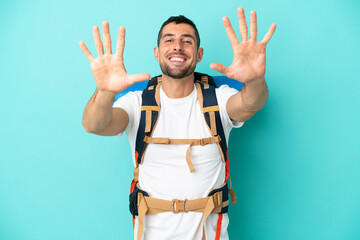 Fototapeta premium Young mountaineer caucasian man with a big backpack isolated on blue background counting ten with fingers