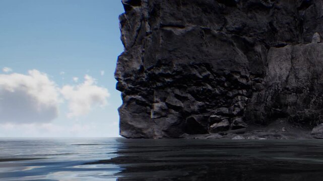 The scene shows a large rock formation rising from the water. Waves gently lap against the base of the rocks. The sky is clear with some clouds visible in the background.