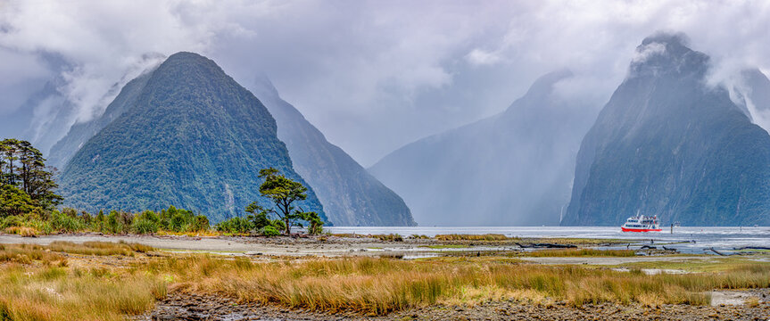Milford Sound mit Mitre Peak im Nebel: Ausflugsboot durchquert den Fjord bei Ebbe, Fiordland-Nationalpark, Neuseeland