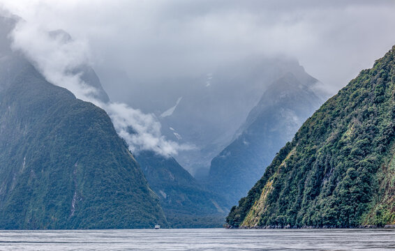Milford Sound mit Mitre Peak im Nebel: Ausflugsboot durchquert den Fjord bei Ebbe, Fiordland-Nationalpark, Neuseeland