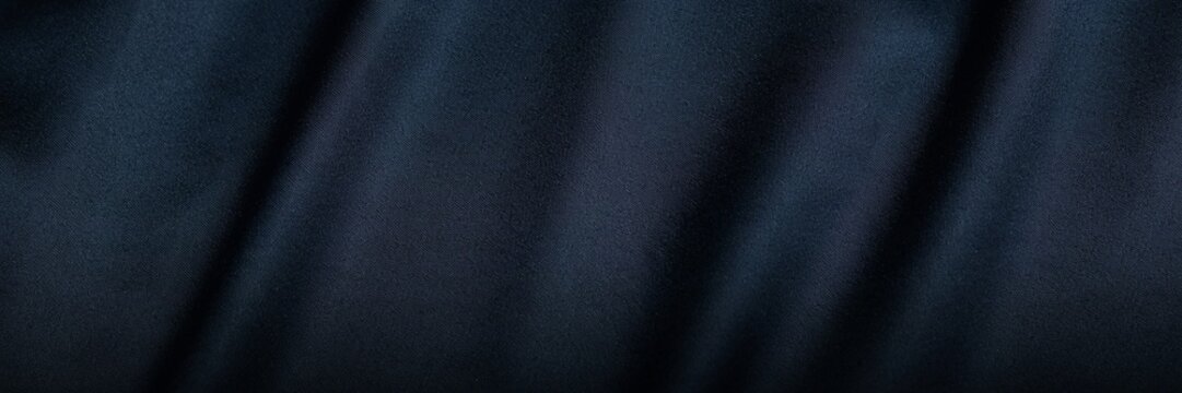 Navy blue velvet fabric texture with soft ripples. Elegant dark blue textile background with luxury silk sheen. Deep indigo cloth material for fashion design and interior upholstery decor.