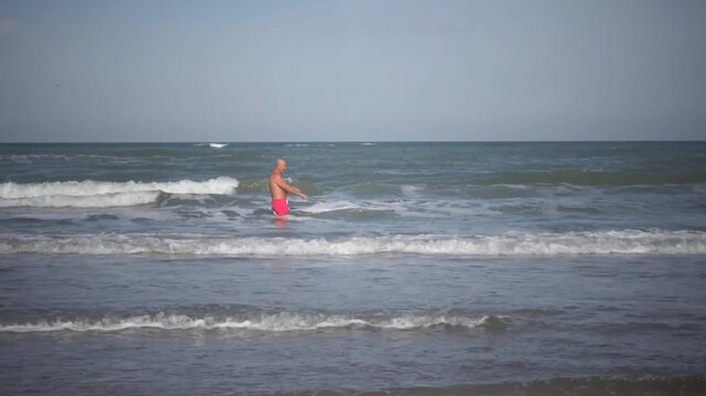 Hirtshals, Denmark A man does morning callisthenics and exercises on a sandy beach on the North Sea in summer. 