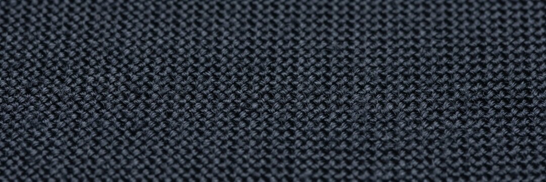 Black nylon webbing texture close-up, durable synthetic strap material for industrial use, dark woven fabric ribbon background, heavy duty textile belt surface for outdoor gear and luggage