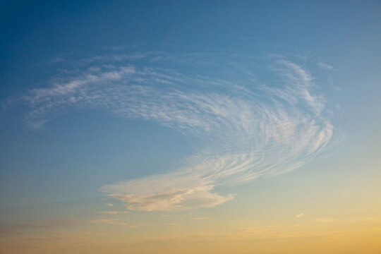 Dramatic wispy clouds in blue evening sky.