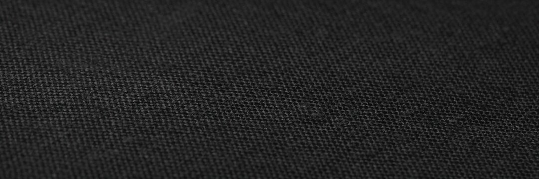 Black fabric texture background, dark charcoal textile material with fine weave pattern, elegant ebony cloth surface for fashion design, minimalist matte black canvas backdrop for mockups