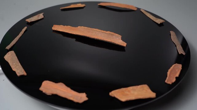 Cinnamon Sticks Rotate on a Black Turntable with a Subtle Reflection, Perfect for Food, Spice, and Culinary Stock Footage