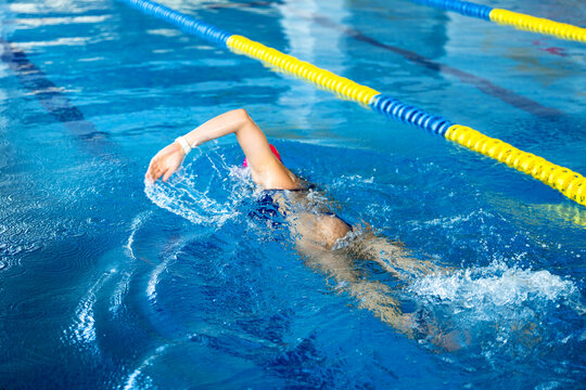 Swimmer doing freestyle stroke in pool, training for endurance and wellness