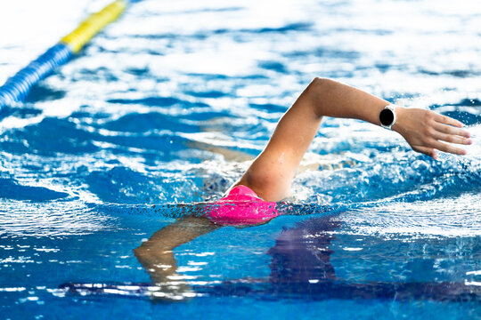 Swimmer's arm emerging from water with wearable device tracking athletic performance