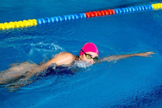 Female swimmer training freestyle stroke in competition pool, pursuing health and improvement