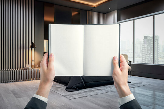 Open blank book held by hands in a modern luxury interior with city view, creative copy space for reading, publishing and design concepts.