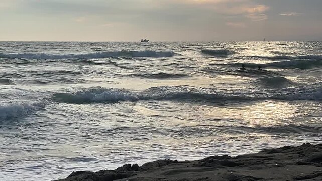 Waves crashing on the sandy beach of at sunset.