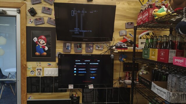 Washington, D.C., USA - September 17, 2025: A retro-style gamer's corner features two screens with classic games, a Mario poster, old cartridges, and a refreshment stand on a wooden wall.