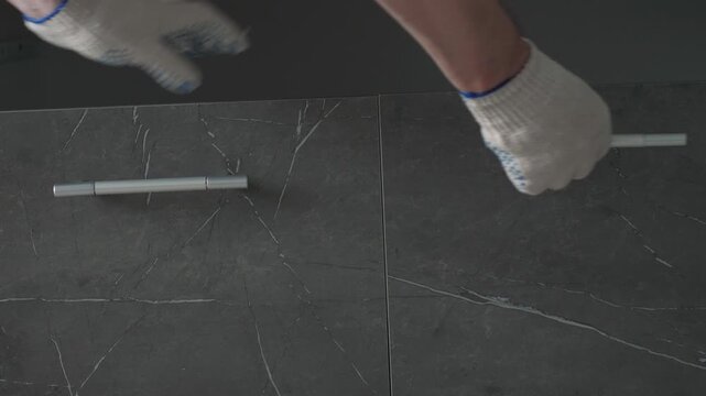 Craftsman opens and tests the closing mechanism of a dark marble kitchen cabinet door. Experienced specialist verifies hardware smoothness and assembly quality during home renovation
