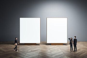 Fototapeta premium Two blank presentation boards with business people in a modern gallery space, advertising mockup and creative communication concept on dark background.