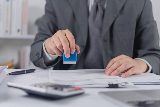 Businessman hand stamping corporate document for official approval and legal certification
