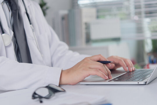 Doctor hands typing on laptop keyboard with stethoscope for online medical consultation