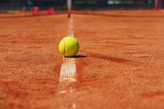  A yellow tennis ball lies on the clay court.