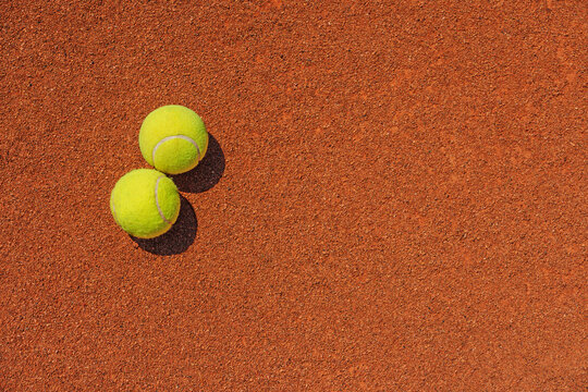  A yellow tennis ball lies on the clay court.