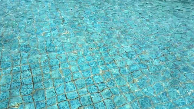 clear blue rippling water in swimming pool with tiled bottom surface