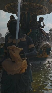 Gilded statues of the historic Fontaine des Fleuves at the Place de la Concorde in Paris, France, with sparkling water cascading down into the basin on a sunny summer day