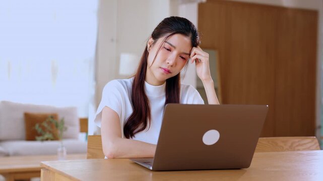 Asian woman laptop home table working indoor young focused casual remote work cozy bright office wooden table thoughtful computer